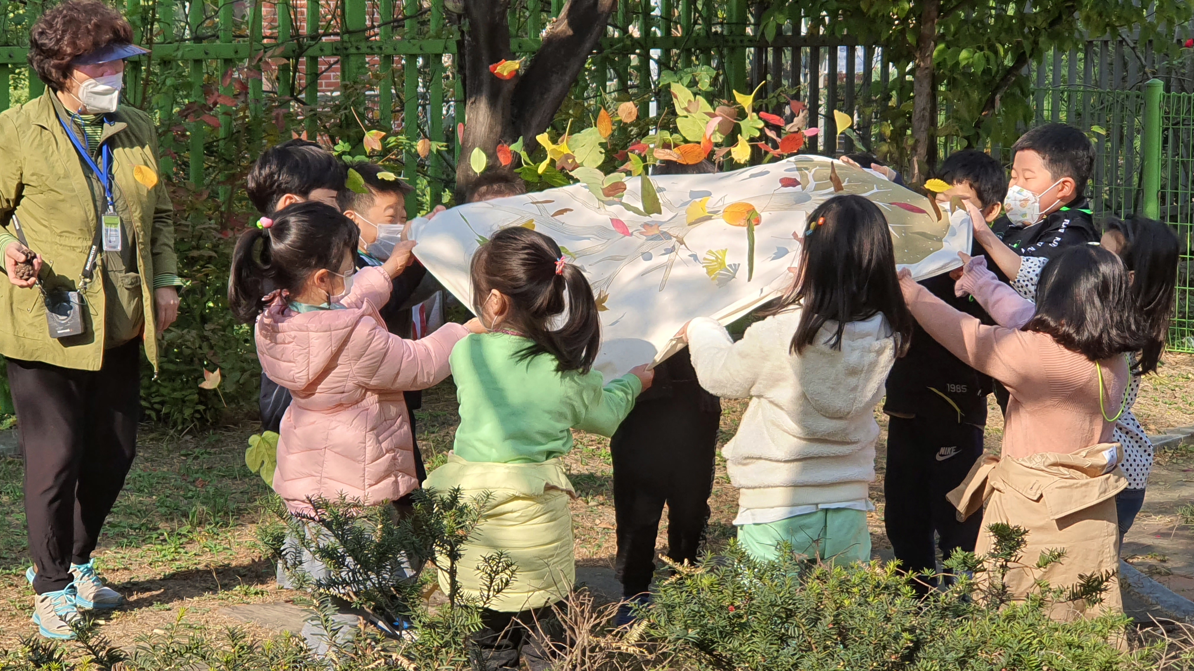 국가환경교육지원단 강사와 수택초등학교 아이들이 학교 숲에서 나뭇잎 관찰놀이를 하고 있다.